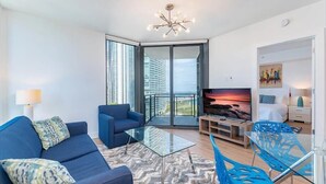 A modern living room with a blue sofa, glass coffee table, and blue chairs.