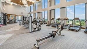 A spacious gym with various exercise equipment, large windows, and a high ceiling. - Experience Reston | Work Desk + Fast WiFi | nr Washington DC (Reston)