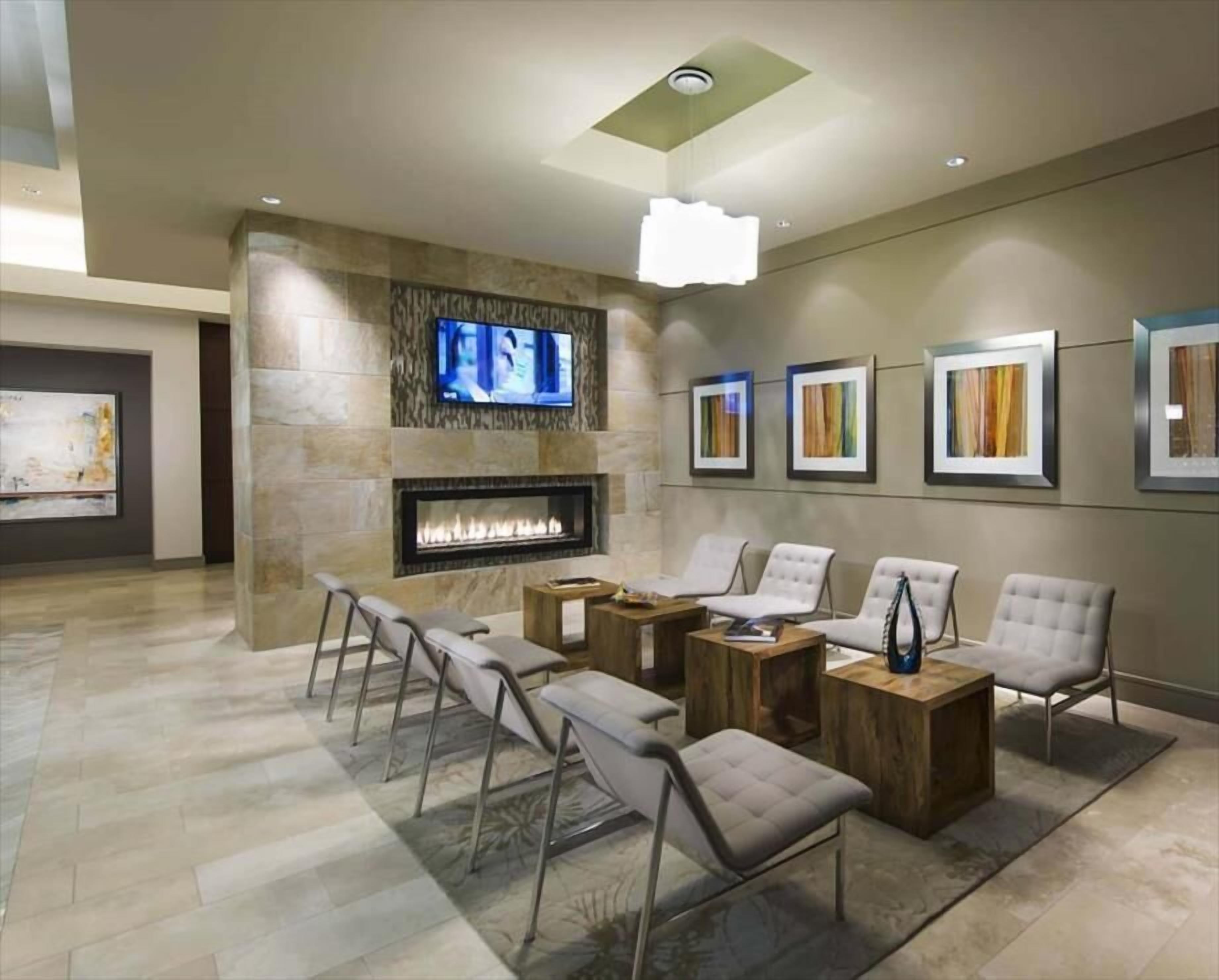 A modern living room with a fireplace, comfortable seating, a flat-screen TV, and framed artwork on the walls.