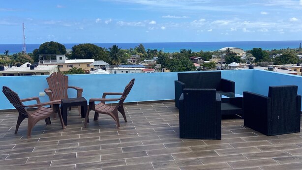 Une terrasse sur le toit, aménagée avec du mobilier d’extérieur et offrant une vue sur l’océan.