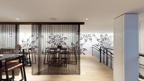 Un interior moderno con comedor, una escalera y una pared decorativa con motivos florales.