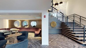 A modern lobby with a seating area, a staircase, and a decorative wall piece.