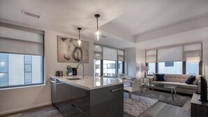 A modern kitchen with a central island, a dining area with a sofa and chairs, and large windows providing natural light.