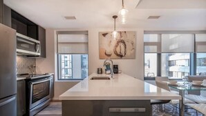 A modern kitchen with a large island, stainless steel appliances, and a large window providing natural light.