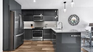 Una cocina moderna con armarios oscuros, electrodomésticos de acero inoxidable y una isla central.