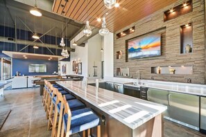 A modern kitchen with a central island, bar seating, and pendant lighting. - Furnished 1BR w/ Shared Fire Pit, Heated pool & BBQ (Menlo Park)