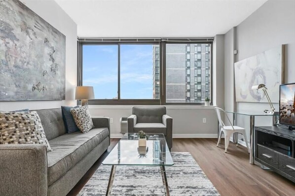 Relax in this stylish living room with a sofa, armchair, and coffee table, offering a view of the city skyline.