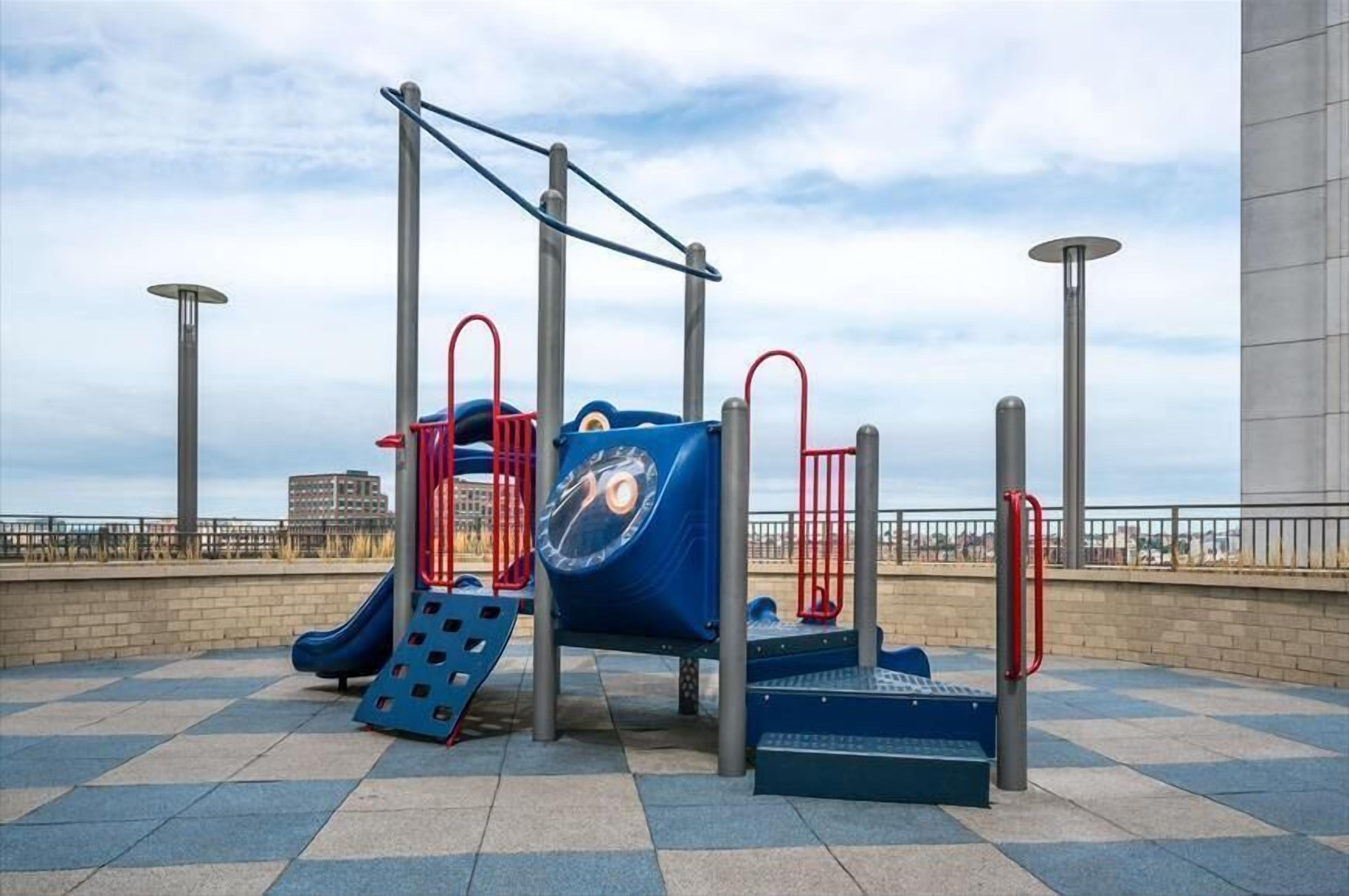 A playground with a slide, climbing structures, and a blue play area.