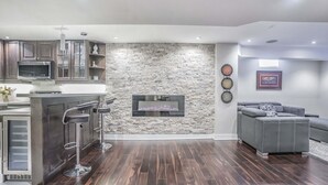 A modern kitchen with a stone accent wall, a built-in microwave, and a bar area. - Charming basement retreat awaits you! (Markham)