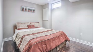 A bedroom with a bed, a window, and a wall-mounted artwork. - Charming basement retreat awaits you! (Markham)