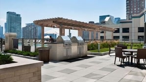 Ein Außenbereich mit Terrasse, einer Pergola, einem Grill und Sitzgelegenheiten.
