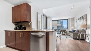 Eine moderne Küche mit Geschirrspüler, Holzschränken und einer Essecke mit Sofa und Tisch.