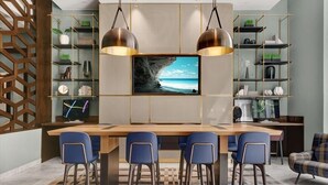 A modern kitchen with a central island, bar stools, and a large flat-screen TV.