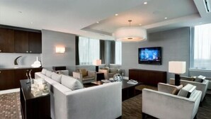 A modern hotel room with a living area featuring a sofa set, a coffee table, and a TV. - Modern 2BR | Fully Equipped Kitchen | Near PATH by GLS (Jersey City)