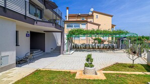 A courtyard with a pergola, a small garden, and a building with a balcony. - Beautiful apartment in Rovinj with WiFi (Rovinj)