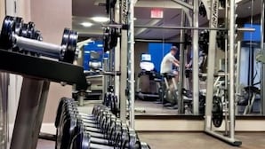 A gym with weightlifting equipment and cardio machines. - Spacious 1BR | Full Kitchen | Near PATH by GLS (Jersey City)