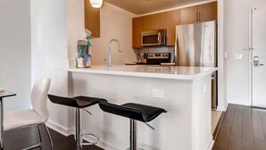 A modern kitchen with a central island, stainless steel appliances, and bar stools.