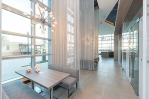Een modern interieur met een houten tafel en bank, grote ramen en een moderne kroonluchter.