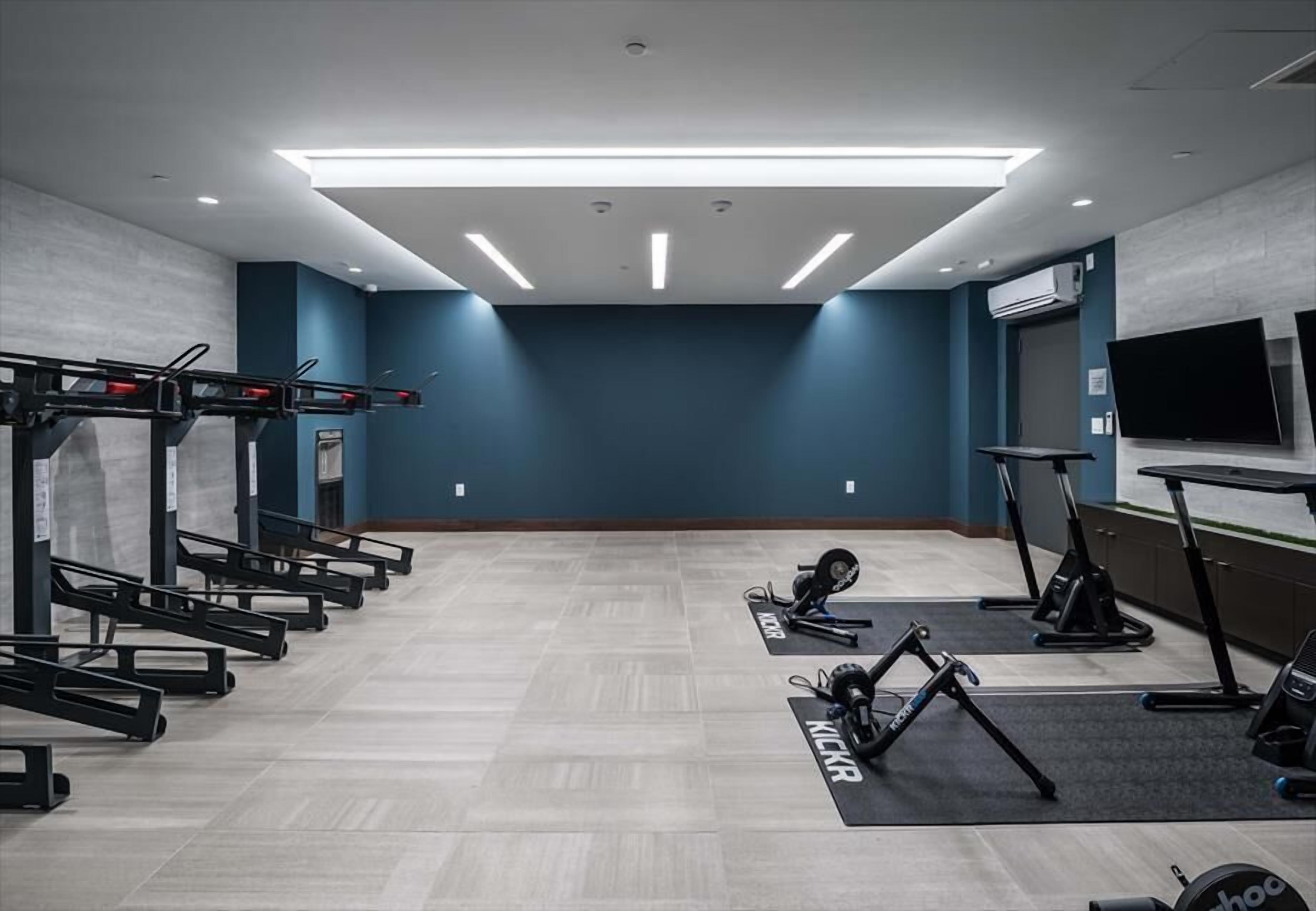 A gym with exercise equipment, a TV, and a large window.