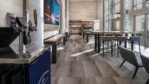 A modern hotel lobby with a coffee bar, seating area, and large windows. - Arlington Virginia 2BR | Crystal City | Easy DC Access | by GLS (Arlington)