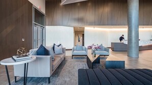 A modern lobby with sofas, a reception desk, and a large pillar. - Arlington Virginia 2BR | Crystal City | Easy DC Access | by GLS (Arlington)