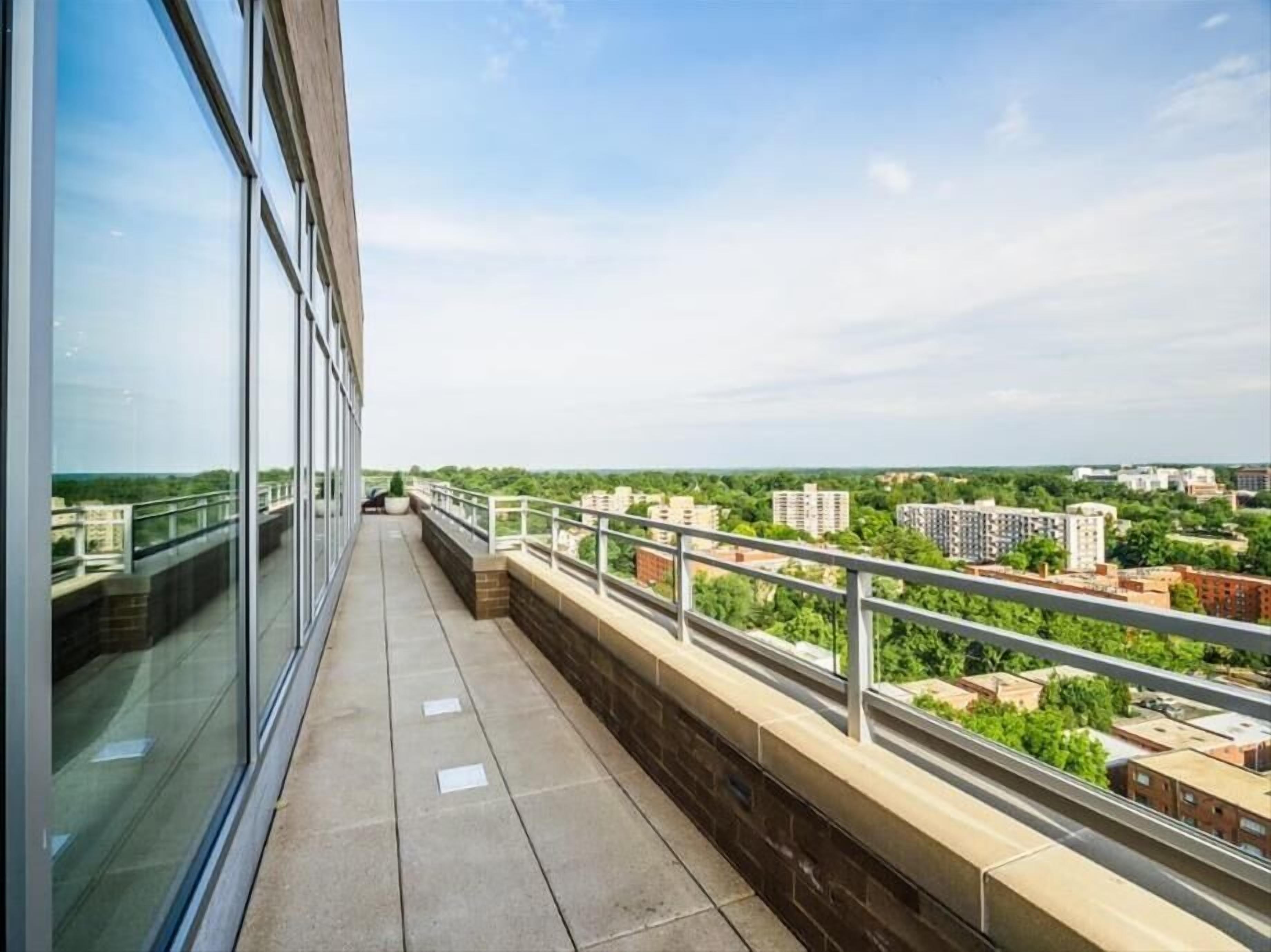 A balcony with a view of a cityscape, including buildings and greenery.