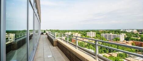 A balcony with a view of a cityscape, including buildings and greenery.
