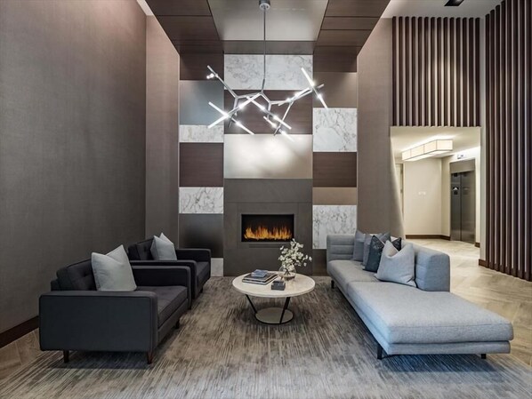 A modern lounge area with a fireplace, two sofas, a coffee table, and a contemporary light fixture.