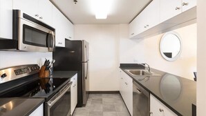 A modern kitchen with stainless steel appliances, white cabinetry, and a black countertop. - Family-friendly 1BR nr Church Square Park |  Riverside (Hoboken)