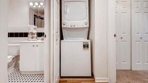 A compact laundry room with a washing machine, dryer, and a small television. - Private & Clean 1BR | Work Remote | Hoboken Riverfront | Easy access to NYC (Hoboken)
