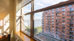 Ein Zimmer mit einem großen Fenster, das auf einen Fluss und ein Hochhaus blickt.
