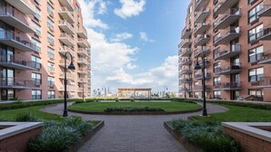 A modern apartment complex with a central courtyard, featuring a circular brick pathway, green landscaping, and a gazebo.
