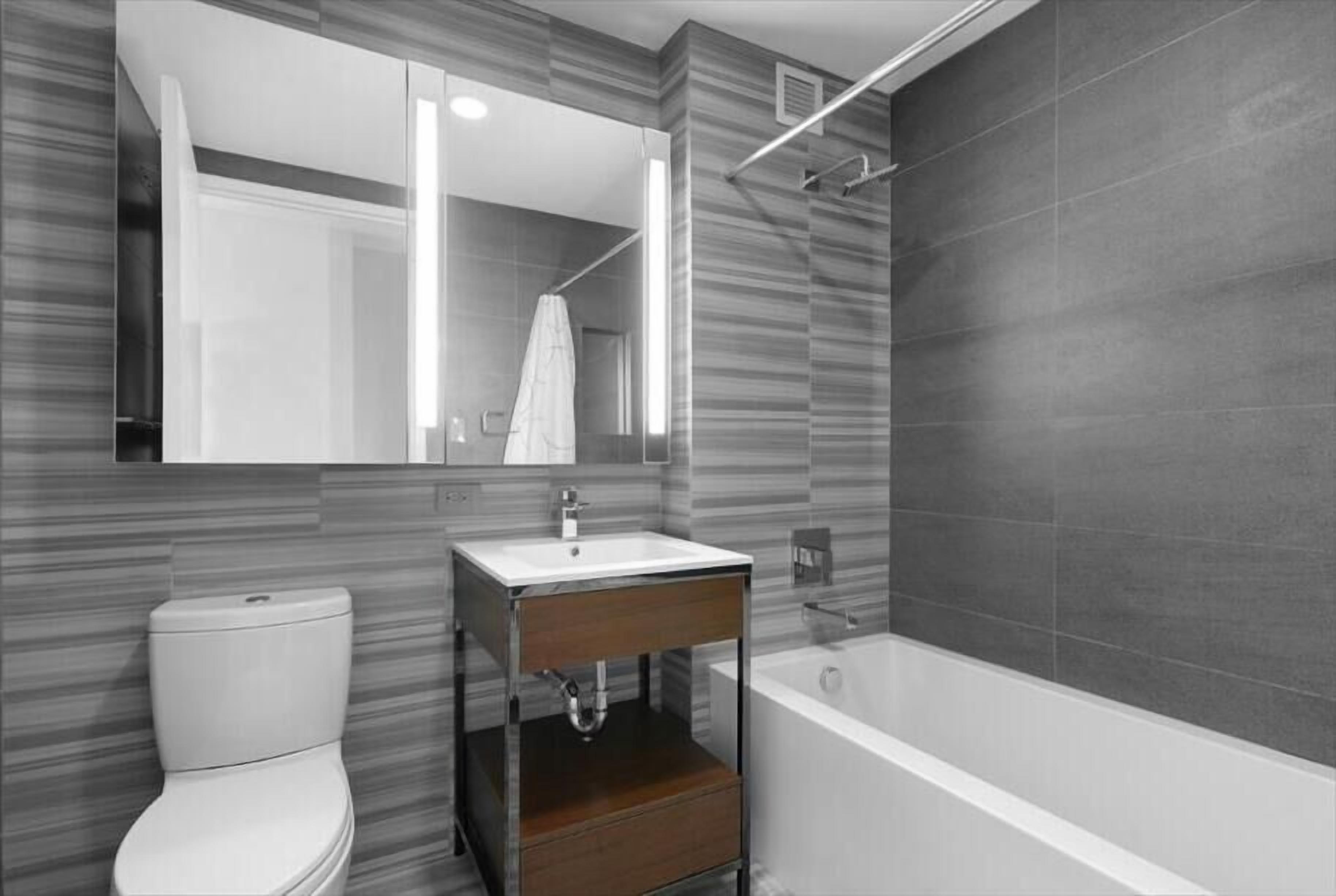 A modern bathroom with a toilet, sink, and bathtub.