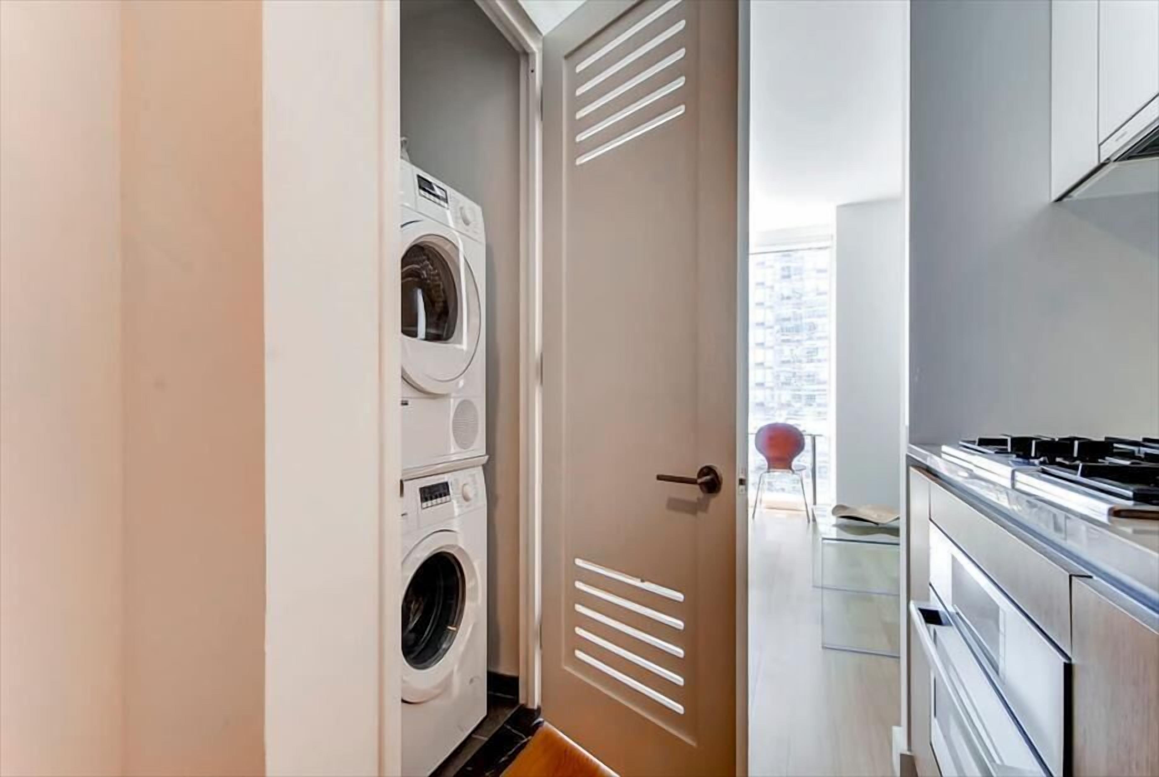 A modern kitchen with stainless steel appliances and a view of the city through an open door.