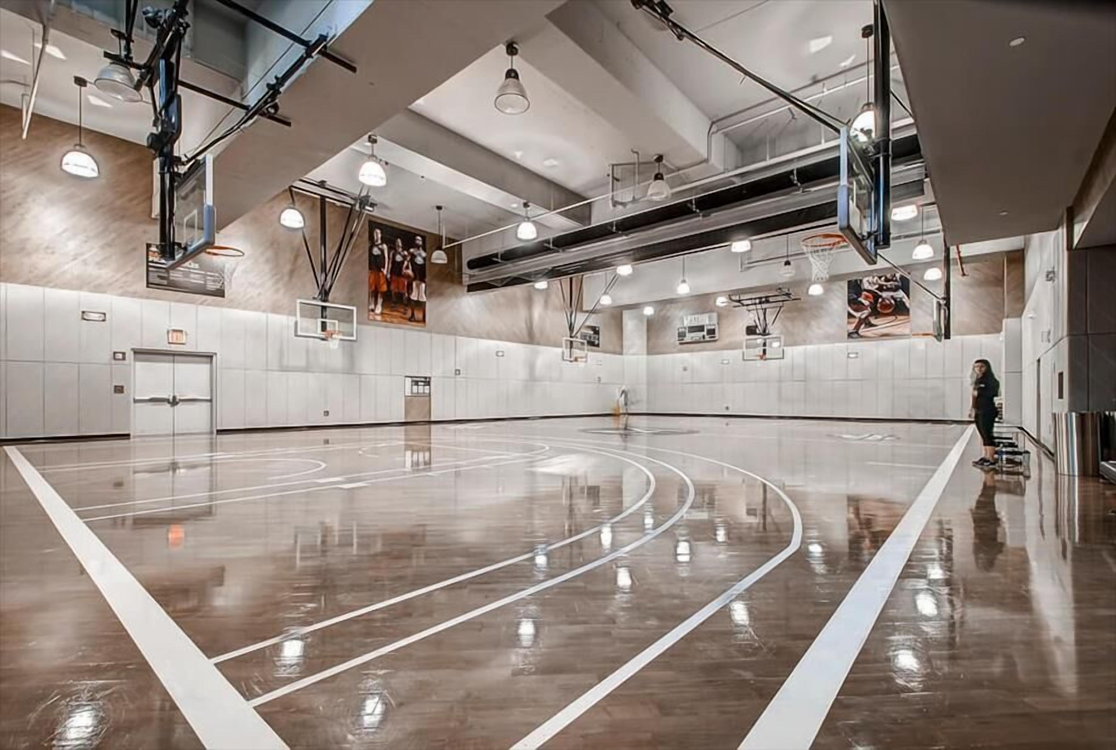 Un vaste terrain de basket-ball intérieur, doté de plusieurs paniers, de hauts plafonds et d’un éclairage moderne.