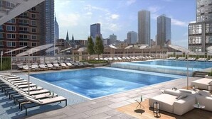 A rooftop pool area with lounge chairs and a seating area, surrounded by high-rise buildings. - Gorgeous Studio | Full Kitchen & Laundry | Midtown West | by GLS (New York)