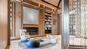 A modern interior with a fireplace, bookshelves, and contemporary seating. - Gorgeous Studio | Full Kitchen & Laundry | Midtown West | by GLS (New York)