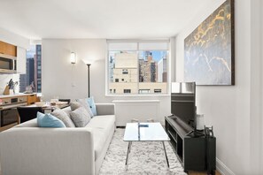 Ein modernes Wohnzimmer mit Sofa, Couchtisch, Fernseher und Blick auf die Stadt.