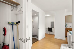 Ein modernes Interieur mit einem Flur, der zu einem Duschbereich führt, einem Esstisch mit Stühlen und einer Küchenzeile mit Schränken und einem Kühlschrank.