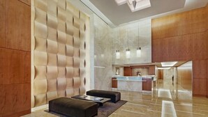 A modern lobby with a reception desk, seating area, and a marble floor. - Gorgeous 1BR | Full Kitchen + Gym | Midtown (New York)