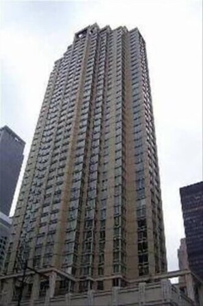 A tall, multi-story building with a uniform facade, likely a residential or office building. - Gorgeous 1BR | Full Kitchen + Gym | Midtown (New York)