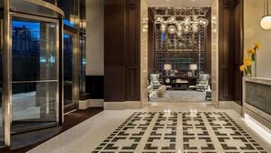 A modern lobby with a patterned floor, a reception desk, and a decorative wall with hanging lights. - Upper West Side Apartments with Hudson River Views (New York)
