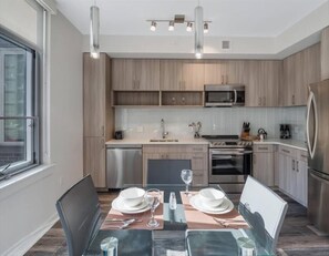 Une cuisine moderne avec des meubles en bois, des appareils en acier inoxydable et un coin repas aménagé pour quatre personnes.