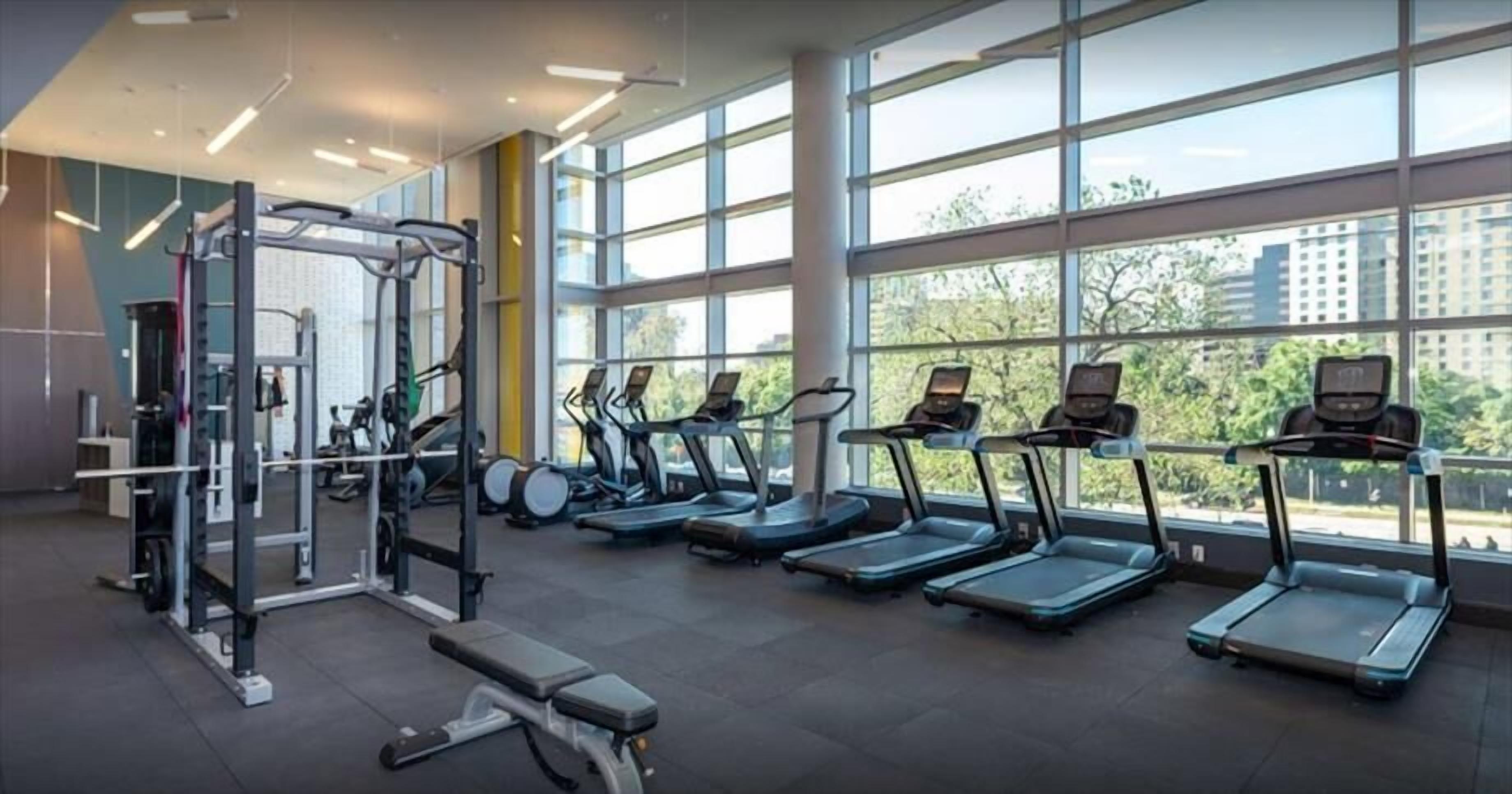 Een sportschool met loopbanden, een krachtapparaat en een bank.