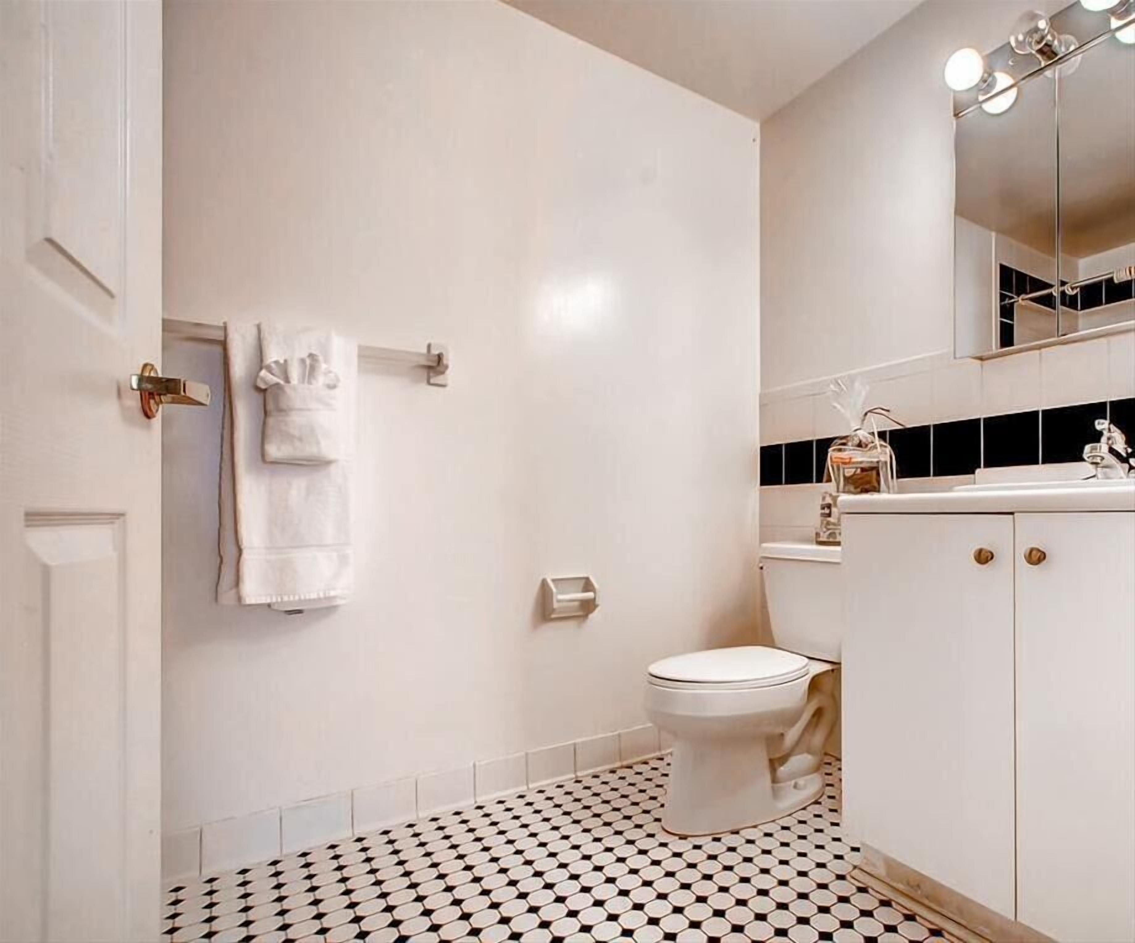 Ein Badezimmer mit Toilette, Waschbecken und einem Spiegel darüber sowie einem Musterfußboden.