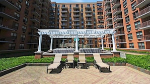 A courtyard with a pergola, outdoor seating, and a view of high-rise residential buildings.