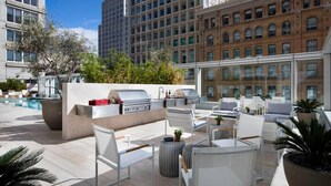 An outdoor patio with a barbecue area, seating, and a pool.