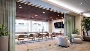 A modern conference room with glass walls, a large table, and several chairs.