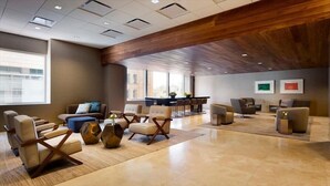 A spacious lobby with modern furniture, a wooden ceiling, and large windows providing natural light.