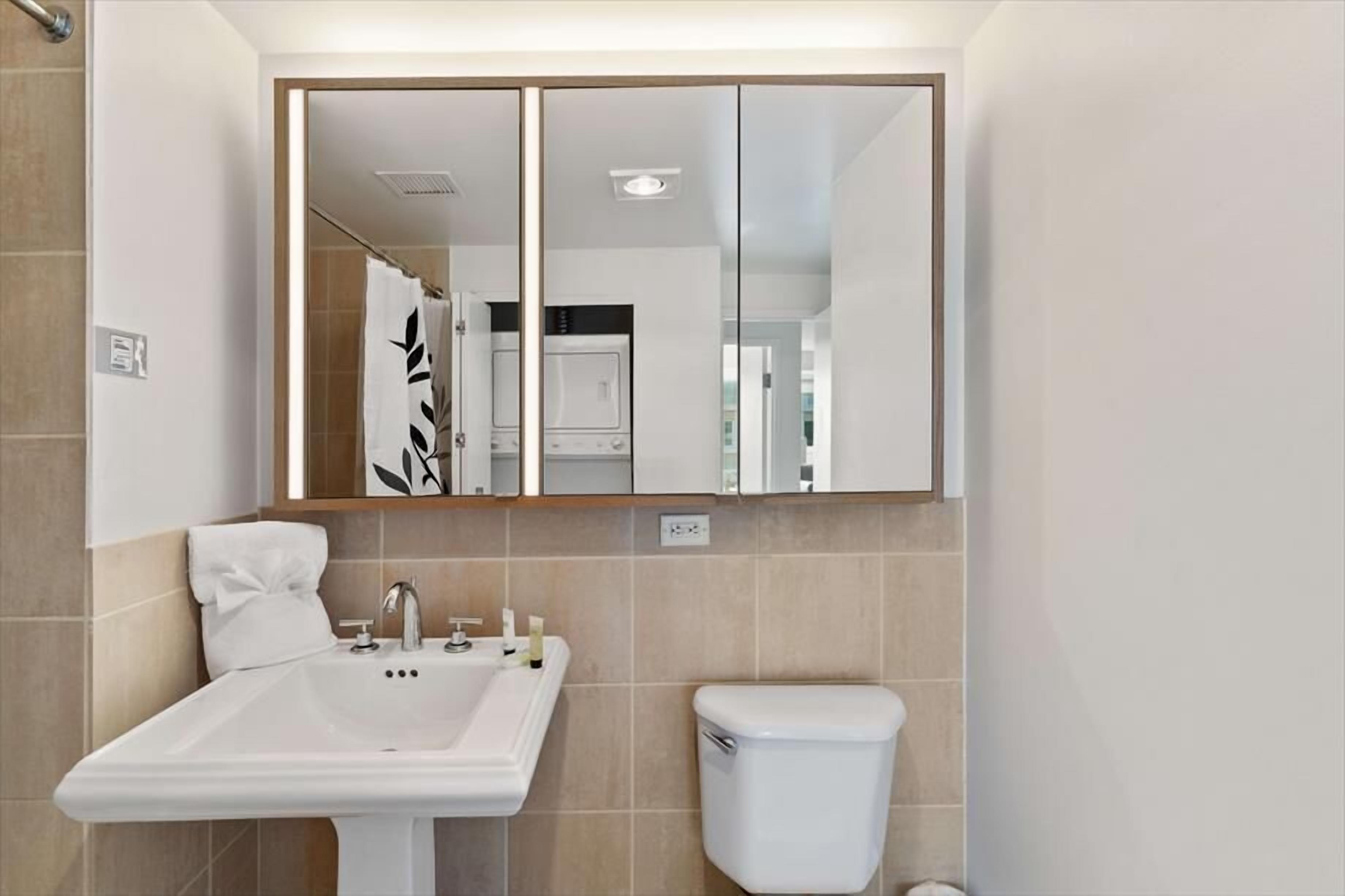 Un bany amb un lavabo blanc, un vàter i un mirall sobre el lavabo.